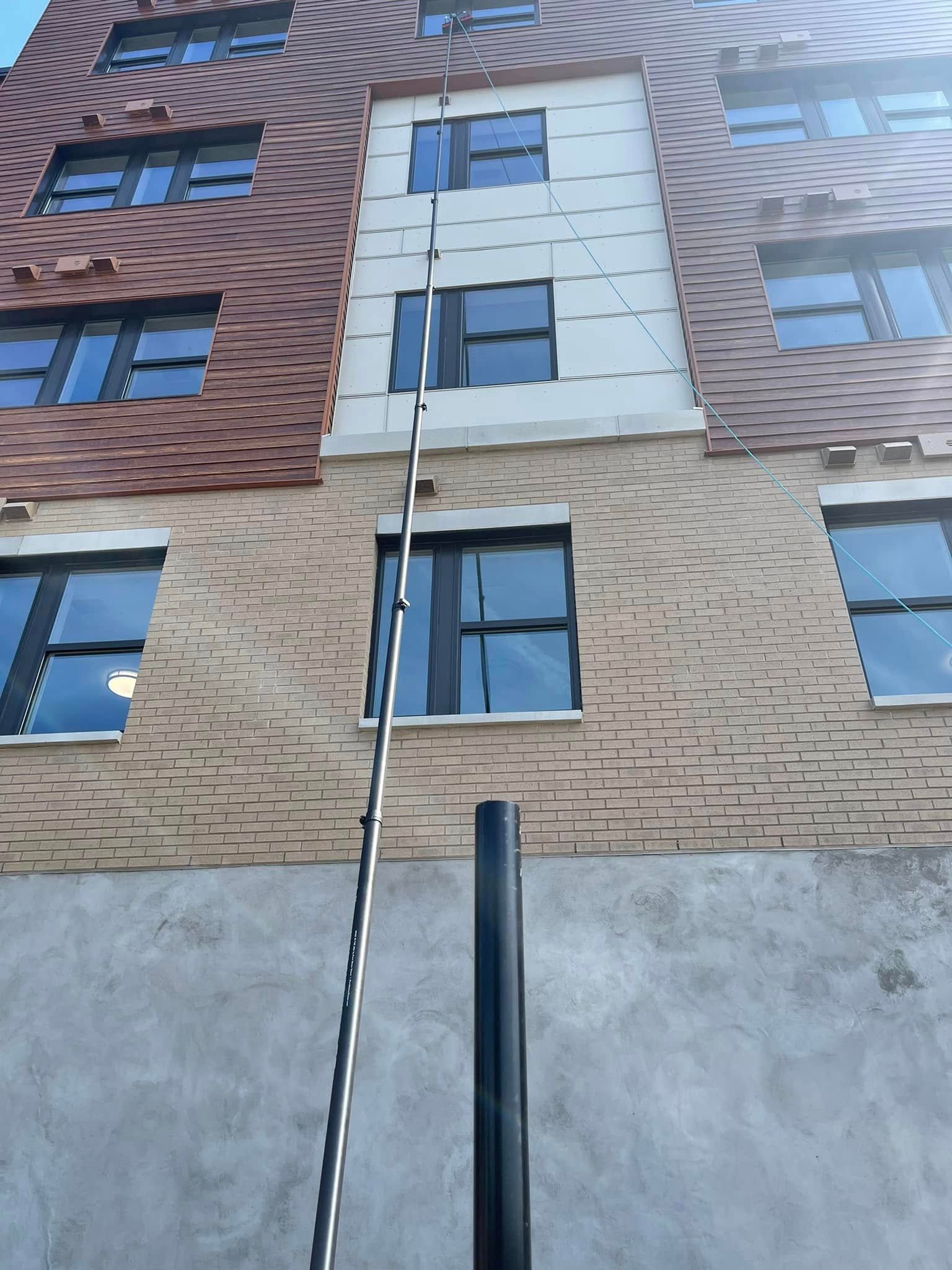 Commercial window cleaner using a water-fed pole on a five-story building